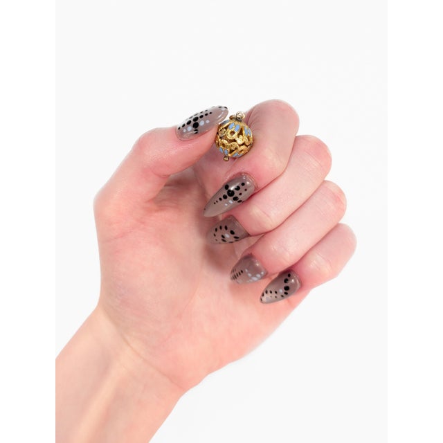 A fine antique Victorian or Aesthetic Movement charm. With a gold plated, reticulated sphere-shaped body. With lilac...