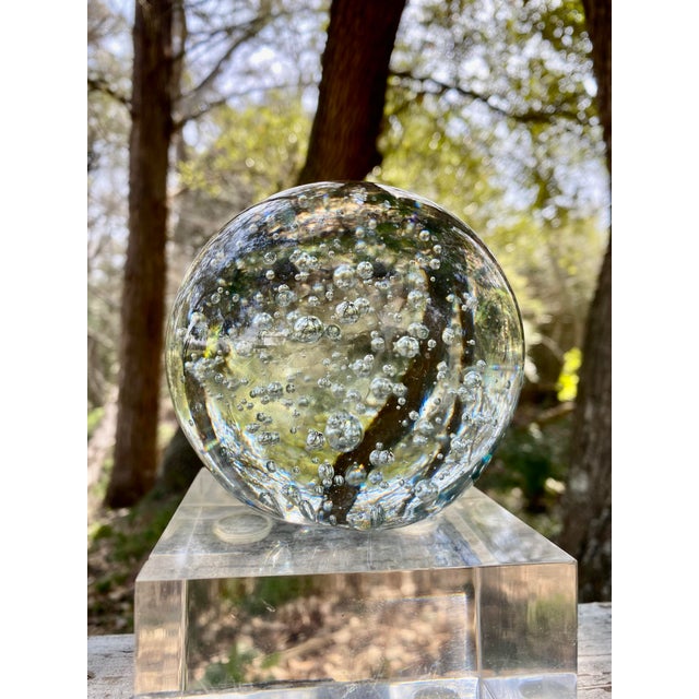 A breathtaking Murano glass ball paperweight, exquisitely hand-blown and adorned with mesmerizing bubbles, seemingly...