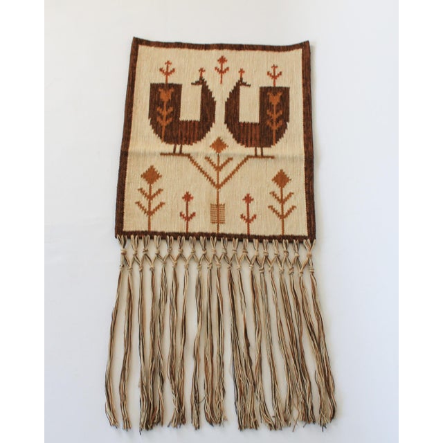 Mid-century woven wool tapestry featuring a cream background with two stylized brown birds and red floral folk motifs. No...