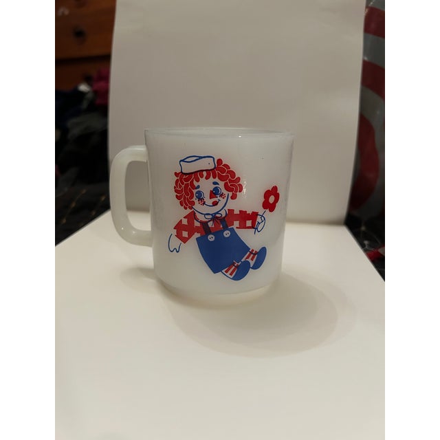 Raggedy Ann on one side, Raggedy Andy on other side of mug. Screen printed design of red and blue not scratched.
