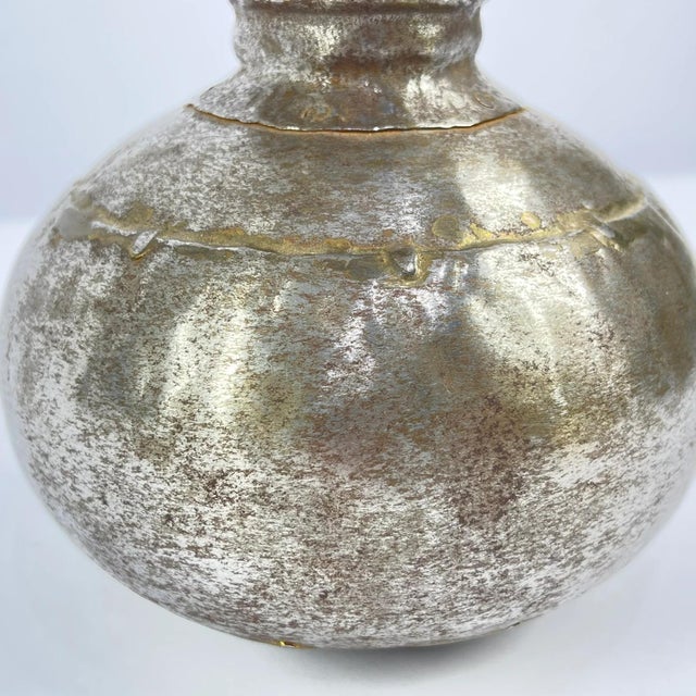 Vintage metal bottle from India with a rounded body. Made from polished metal with visible wear and repair marks. This...