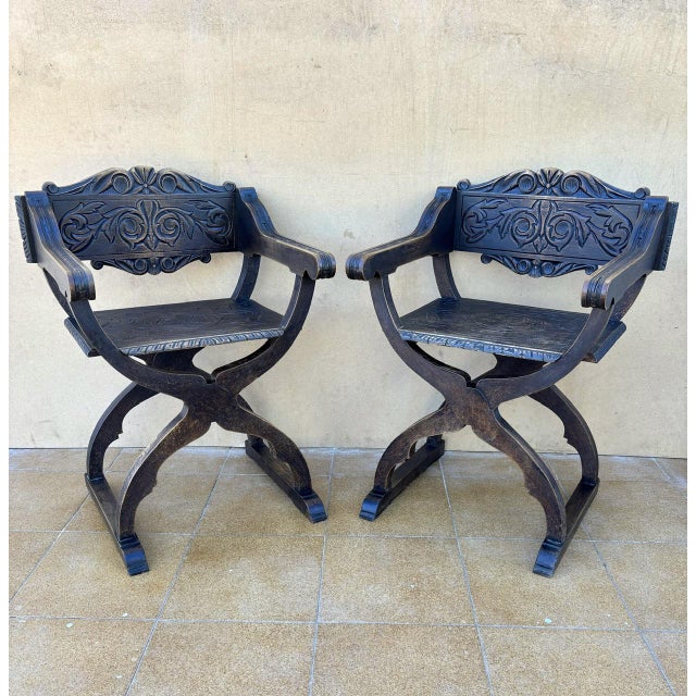 Beautiful pair of Spanish Renaissance Revival Savonarola chairs, crafted in solid wood and richly carved with scrolling...