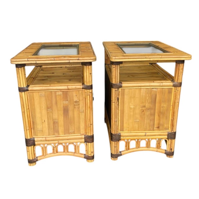 A pair of vintage split bamboo nightstands. Each table has a glass-inset top that showcases the bamboo frame beneath, plus...