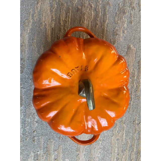 A Staub 3.5 quart cast iron dutch oven in the form of a pumpkin, made in France, with authentic glaze mimicking the colors...