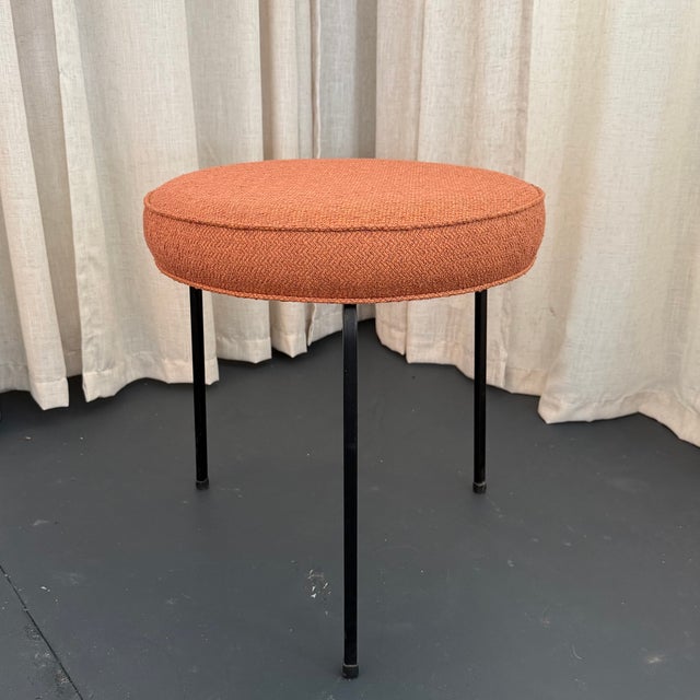 This mid-century modern vanity stool balances structural minimalism with a vibrant, inviting touch of color. The thick,...