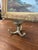 This likely antique brass toned hardware component is a three-pronged hook mount, likely used as a base for a wall-mounted...