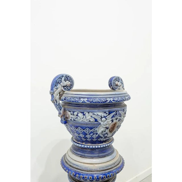 Pedestal made of ceramic in the form of a column with a pot with two handles. Decorated in blue and gray with little...