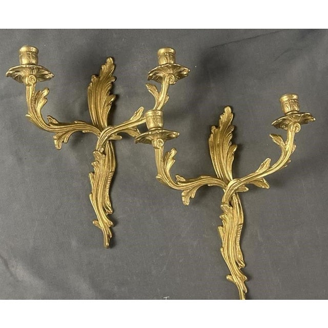 A gorgeous pair of antique French Rococo style gilt brass candelabra two arm candle wall sconces. These beautiful sconces...