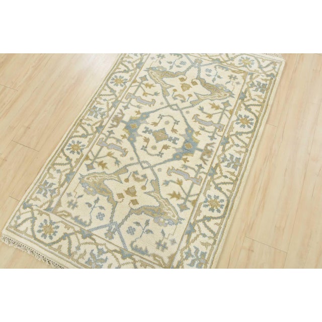 A modern tribal Oushak rug hand-knotted with an all-wool pile on a cotton foundation. This oriental rug features a central...