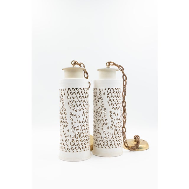 Pair of cylindrical white ceramic pendant lights, with an allover pierced lattice of geometric forms and cut-out cherry...