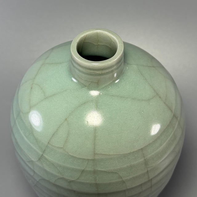 This antique Chinese Longquan celadon meiping vase features distinct horizontal ribbed lines across the body, covered in...