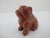 Hand-carved red jasper gemstone figurine of a seated bulldog, recognizable by its wrinkled face and stocky build. Polished...