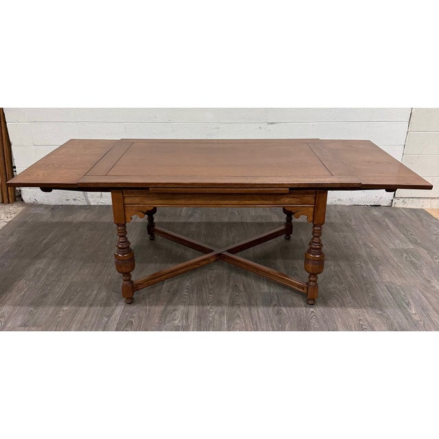 This is a gorgeous vintage solid oak Old English Tudor or Jacobean Revival style draw-leaf dining table featuring turned...