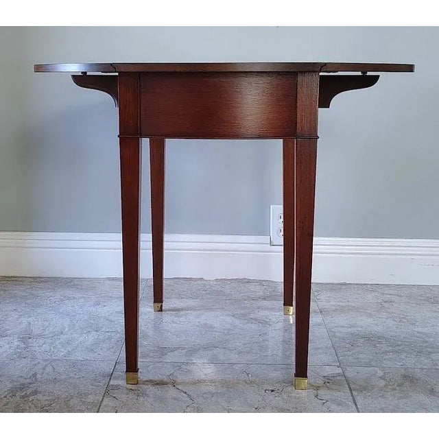 This beautiful traditional Pembroke table is made by Baker. It is made of solid mahogany wood. The tabletop has swirl...