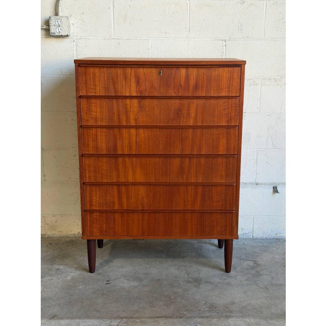 This tall storage piece features a sleek rectilinear silhouette housing six spacious pull-out drawers. Its clean...
