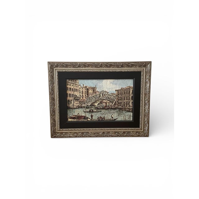 A serene Venetian canal scene featuring a historic bridge and surrounding architecture. The artwork’s textured, tapestry-...