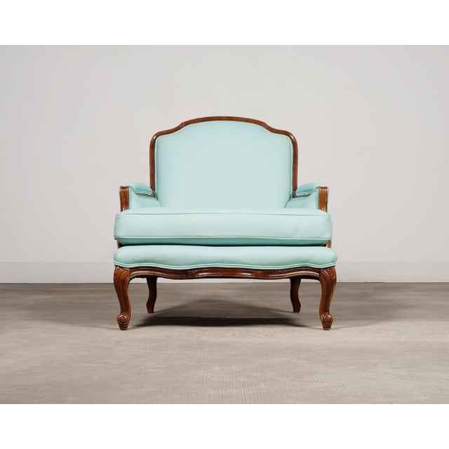 A whimsical French bergère armchair with matching ottoman, executed in the Louis XV, or French Provincial taste. The...