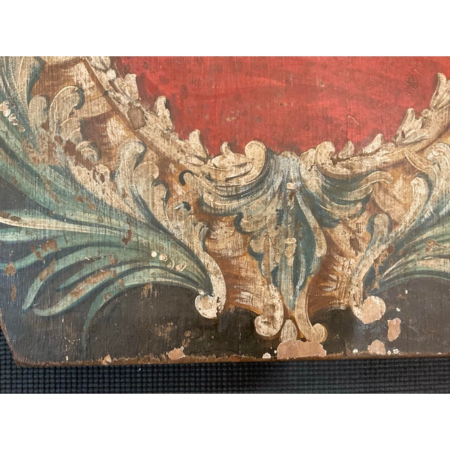 A striking antique Italian hand-painted decorative panel featuring a classical heraldic cartouche surrounded by scrolling...