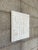 Textured relief wall art with a geometric, grid-like composition. The surface features repeating abstract forms and...