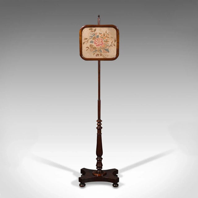 This is an antique adjustable pole screen. An English, Rosewood needlepoint fire shield, dating to the Regency period,...