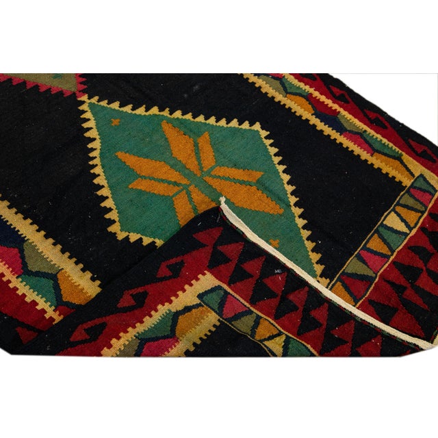 Beautiful kilim handmade wool runner with a dark brown field. This Vintage flatweave rug has green, pink, and goldenrod...