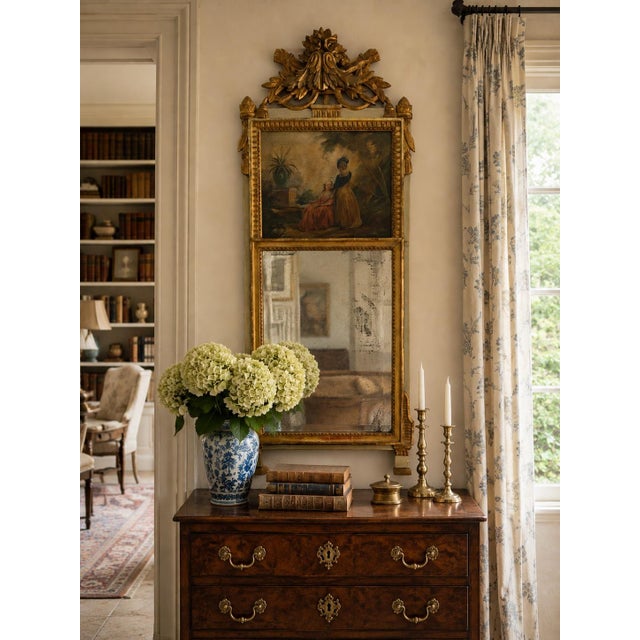 An unusually elegant late 19th century French trumeau mirror combining carved giltwood, antiqued mirror glass, and a...
