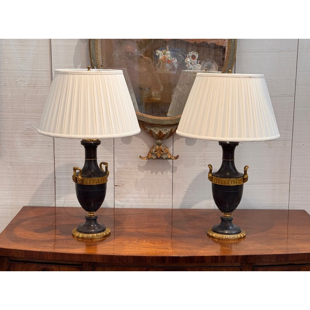A handsome pair of Empire style table lamps, each modeled as a classical urn in dark patinated bronze with a pleasing...