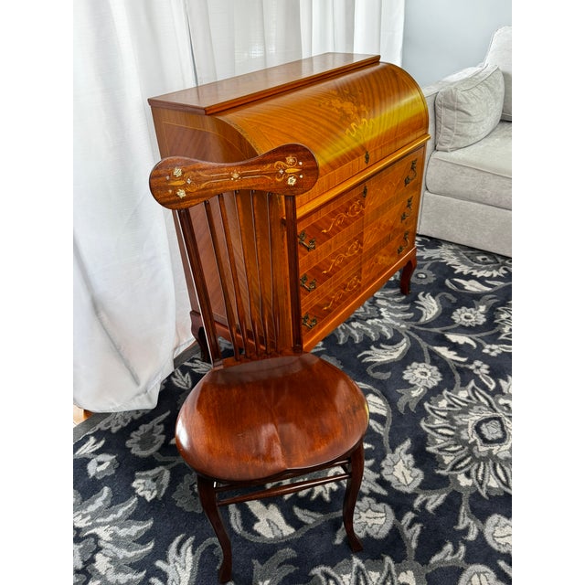 A distinctive vintage writing set featuring a traditional roll-top secretary desk and coordinating wooden chair with...