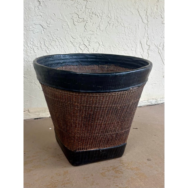 Hand woven 19th-century Thai grain basket crafted from rattan and natural materials with a substantial black lacquered rim...
