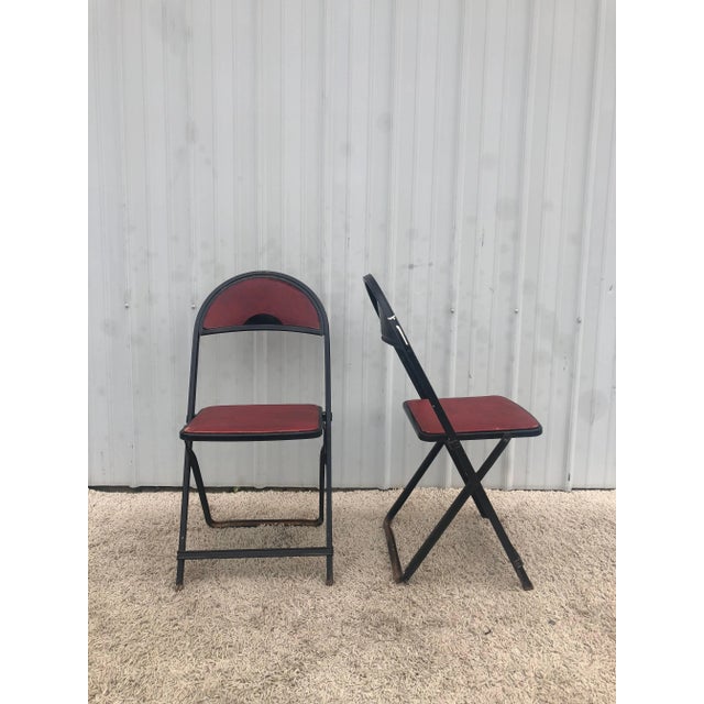 This vintage pair of folding chairs features solid steel frame, original black paint, vintage red vinyl seat & seatback,...