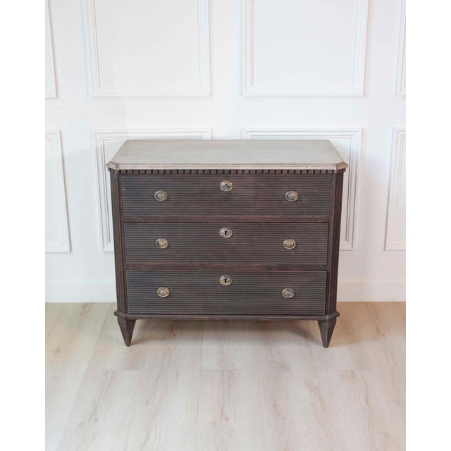 A beautifully tailored Swedish Gustavian-inspired three-drawer chest, crafted with the refined restraint and symmetry that...