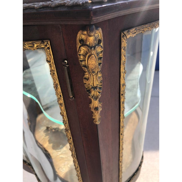 An antique French Louis XV style display vitrine with single door opening to shelved interior, bronze ormolu and raised on...