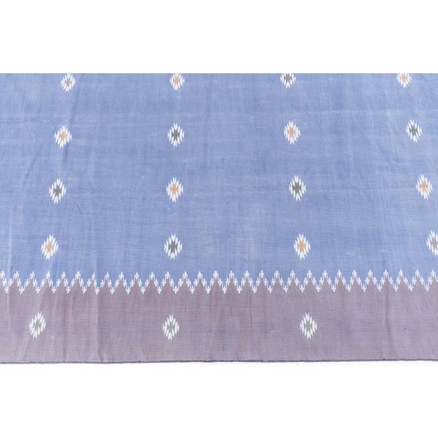 This vintage 1955 Indian Dhurrie rug beautifully illustrates the harmony between traditional craftsmanship and mid-century...
