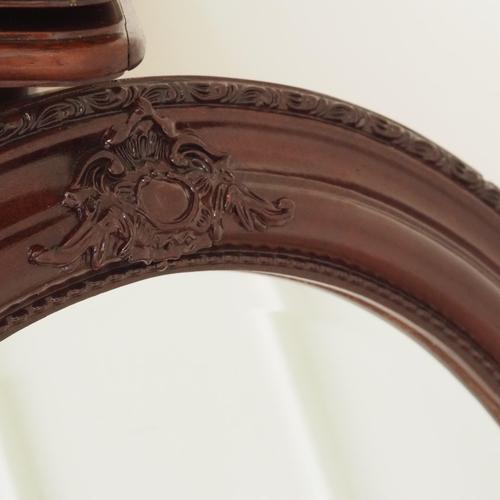 Oval wall mirror with a dark brown frame and ornamental details. Newly crafted piece inspired by historicist mirror...