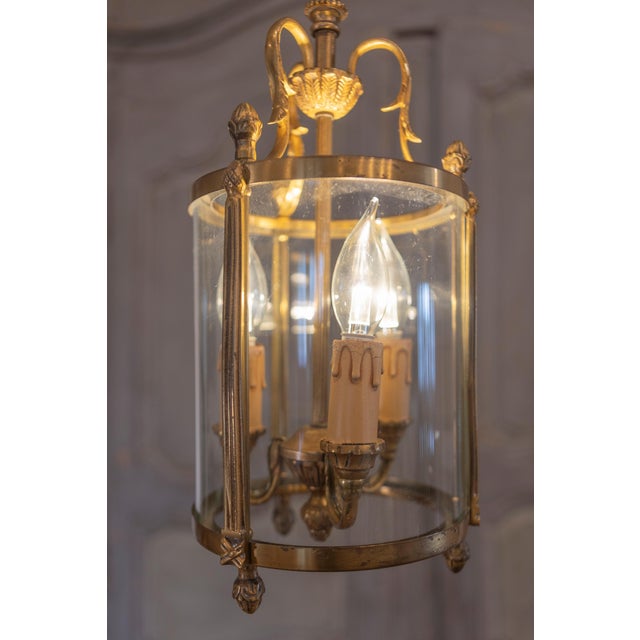 A stunning French brass lantern from the 20th century, featuring a beautifully detailed frame with an aged patina that...