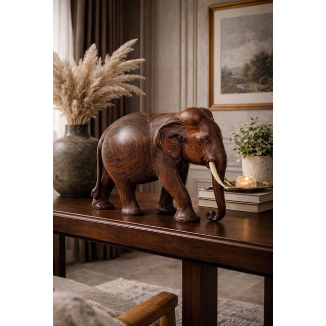 Hand-carved teak elephant sculpture dating to the mid-20th century, likely 1960s. Carved from a solid block of richly...