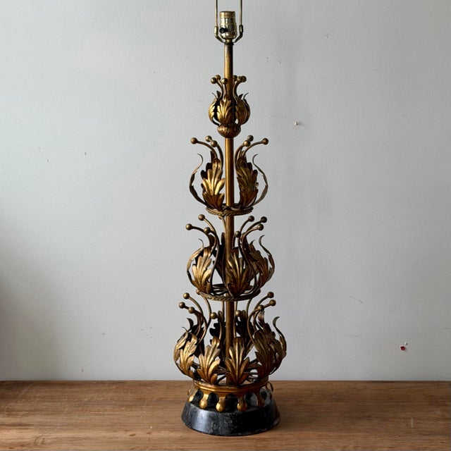 Italian mid-century table lamp in gilt tole with tiered acanthus leaf motif and sculptural vertical form. Set on a dark...