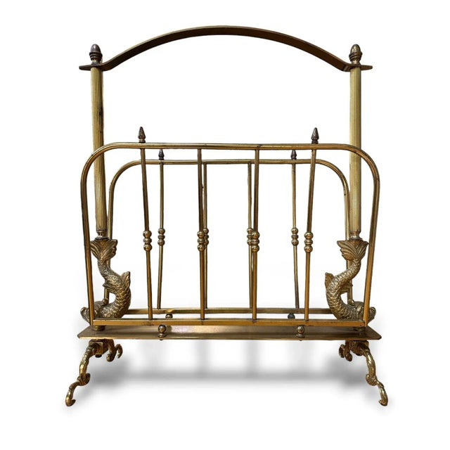 Neoclassical brass magazine rack attributed to French designer, Maison Jansen. This item is unsigned with dolphin form...