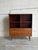 This beautiful storage unit features an upper open display layout with shelves sitting above a lower drop-front cabinet....