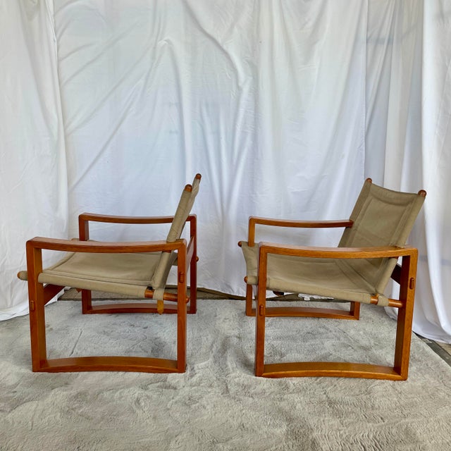 Handsome pair of safari chairs with tan canvas upholstery and solid teak frames doweled at back joints for easy fold-down....
