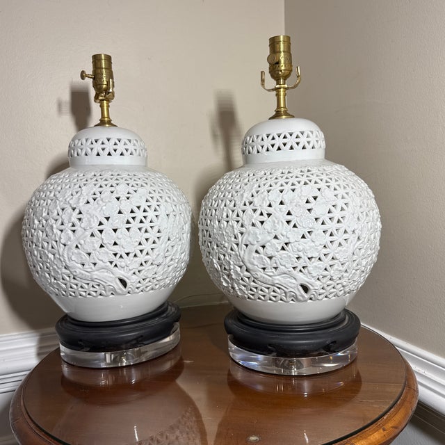 A pair of white glazed ceramic reticulated/pierced ginger jar table lamps. Each features intricate geometric lattice...