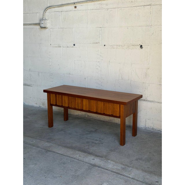 This exceptional entry bench displays a striking linear profile accented by an architectural, textured block front design....