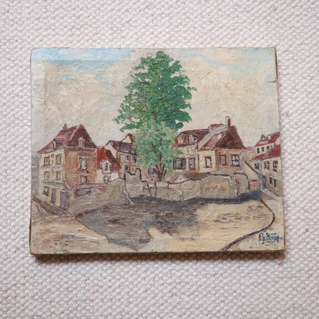 This 20th century French village square painting captures the quiet charm of a quaint European streetscape with soft...