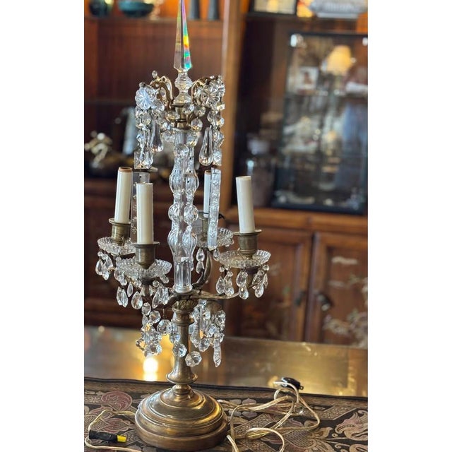 Elegant crystal lamp with brass base. 4 arms and center column with crystal finial 12” wide It appears to have been...