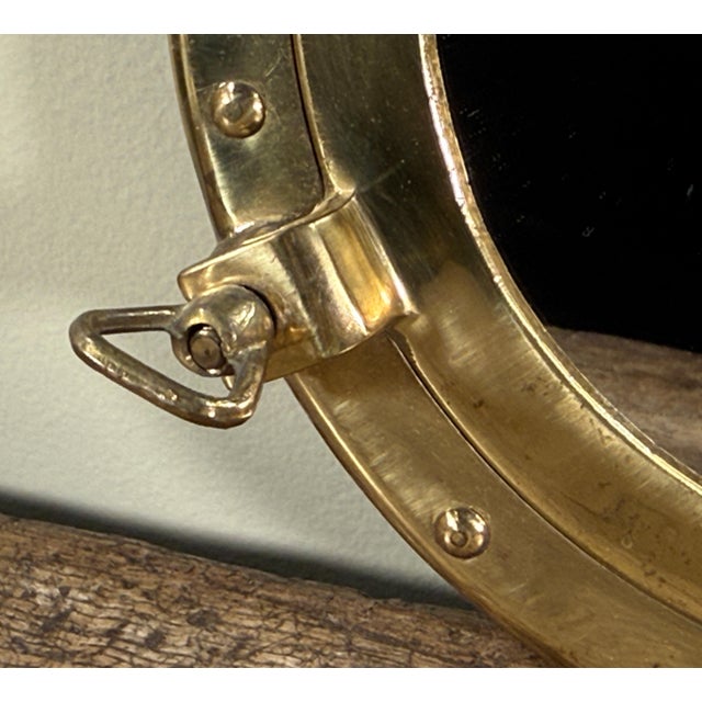 This nautical brass porthole mirror features a circular form designed to resemble a ship's porthole with rivet detailing...