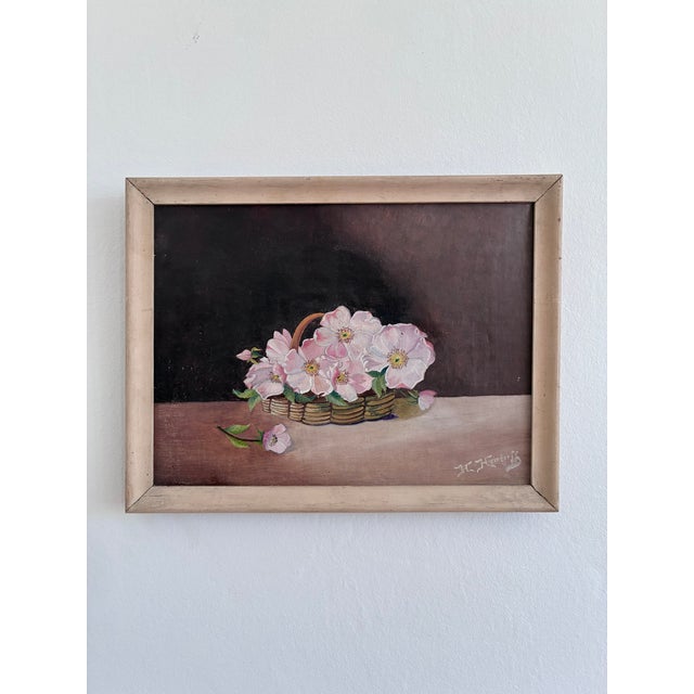 Set of two vintage original flower oil paintings showing floral still lifes in woven baskets, placed on a table against a...