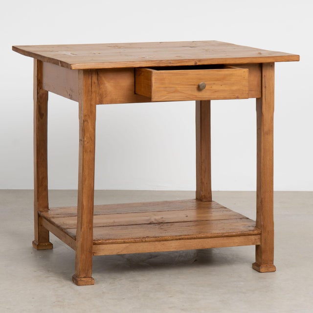 This delightful country pine table with clean lines and single drawer and lower shelf stands on straight legs and will...