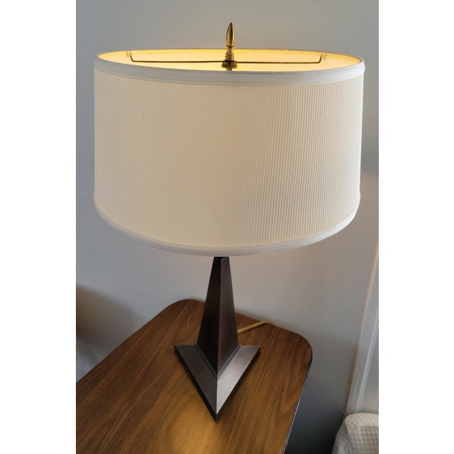 The triangular base of this 26-inch bronze patinated lamp supports a tapering three-sided obelisk bisected by a brass...