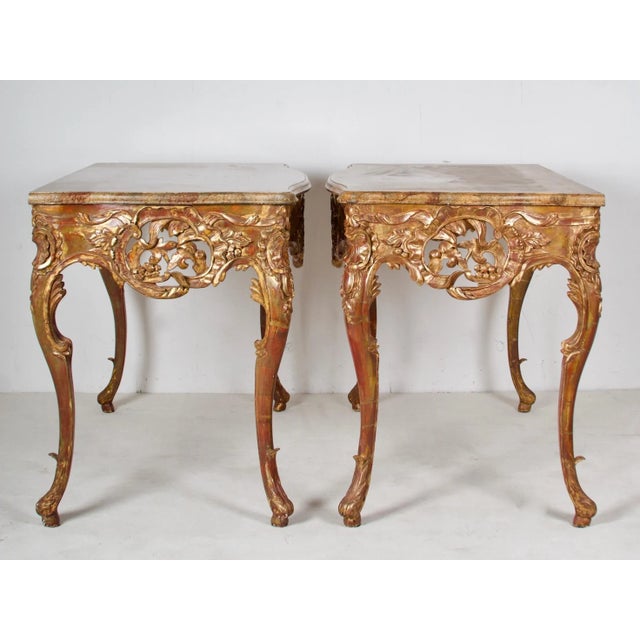 A playfull and flamboyant pair of painted and gilded, hand carved console tables, finished with a nicely done faux marble...