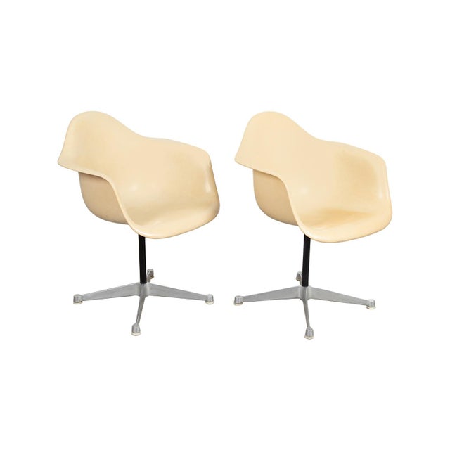 A pair of Mid-Century Modern fiberglass swivel armchairs designed by Charles Eames for Herman Miller. The fiberglass...